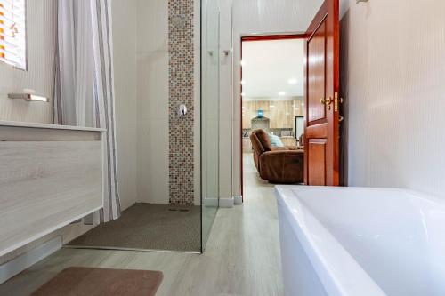 伯诺尼RSA Lodge的带浴缸和玻璃门的浴室