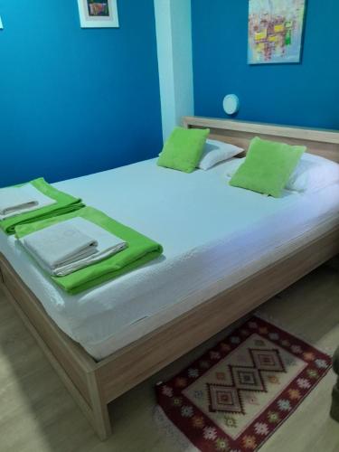 莫斯塔尔Apple Line Appartments的一张带白色床单和绿色枕头的床