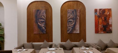 卡萨布兰卡Unico Hotel & Spa Casablanca的墙上设有餐桌和肖像的用餐室