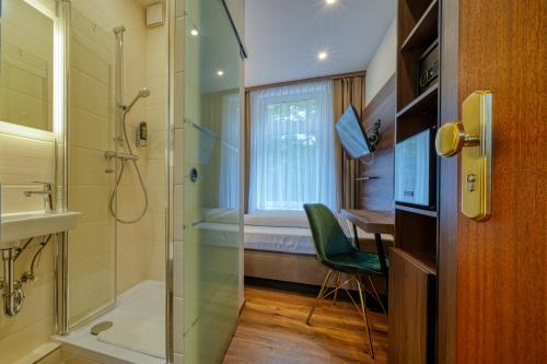 施塔德Zentrum Hotel Stade的带淋浴和盥洗盆的浴室以及书桌。