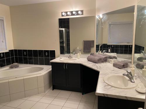 阿贾克斯Adorable Full house in Ajax Incl Basement的浴室配有2个盥洗盆、浴缸和浴缸。
