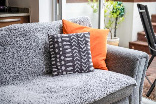 伦敦Gorgeous Kentish Town Flat的灰色的沙发上放着橙色枕头