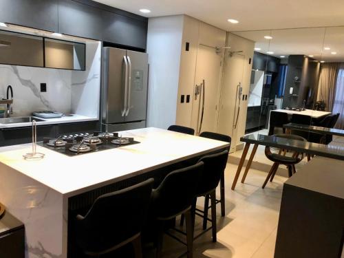 若昂佩索阿Apartamento moderno的厨房配有炉灶和带椅子的柜台。