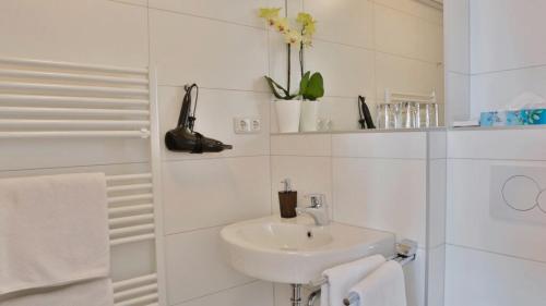 纽伦堡达斯福尔克公寓酒店的白色的浴室设有水槽和淋浴。