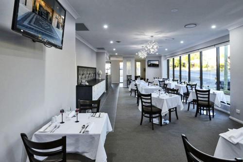 帕克斯天文菜汽车旅馆 的餐厅配有白色的桌椅和电视