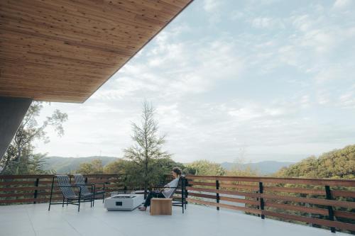 ShioSOOTHE FOREST的坐在阳台上的椅子上,眺望着群山