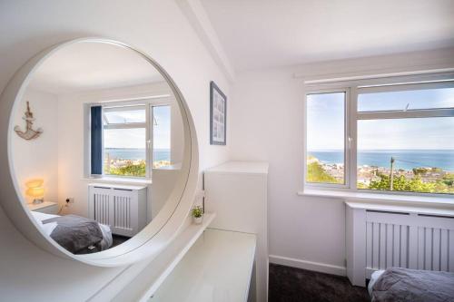 纽基Newquay Sunset & Sea View Apartment in Town Centre的白色客房内的镜子,配有床和2扇窗户