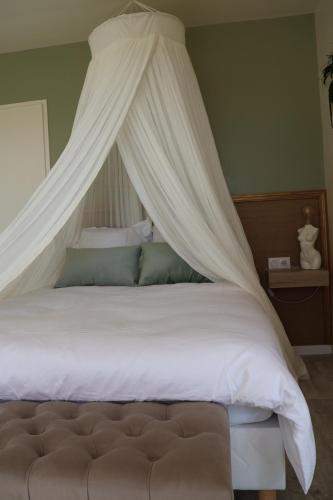 AmillyLes gîtes coquins的卧室配有带白色床单和枕头的天蓬床。