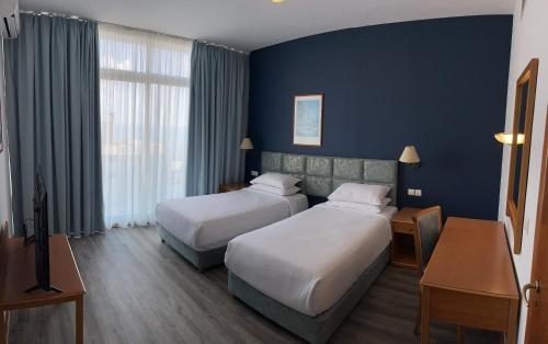 贝鲁特El Sheikh Suites Hotel的两张位于酒店客房的床,拥有蓝色的墙壁