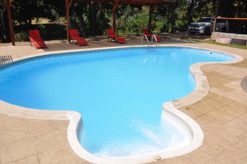 圣玛尔塔AKUAIPPA HOSTAL RESTAURANT的大型蓝色游泳池,配有红色椅子