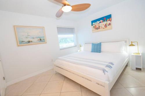皮尔斯堡Hutchinson Island Beach House - Sleeps 32 - 8 BD的白色卧室配有床和吊扇