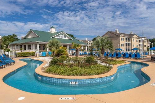 默特尔比奇港湾明灯蓝绿度假酒店的度假村的游泳池,设有蓝色椅子和建筑