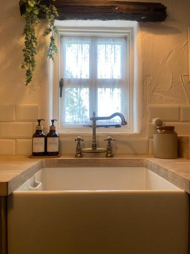 TiragarvanThe Nest Quaint Luxury Cottage Getaway的带窗户的厨房内的白色水槽