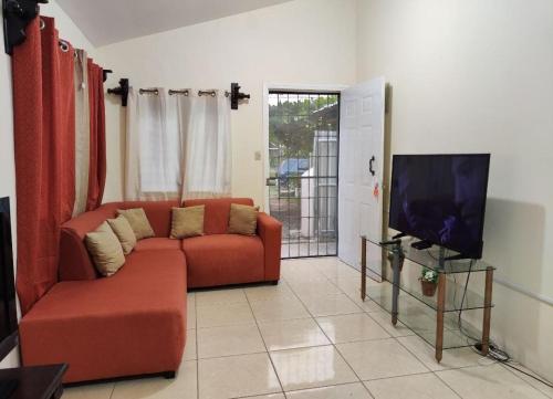 拉塞瓦Alojamiento en La Ceiba的客厅配有红色沙发和平面电视