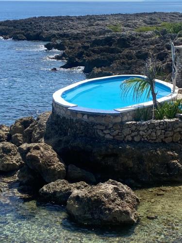 Robins BayForever Cottage的靠近海洋的岩石上的游泳池
