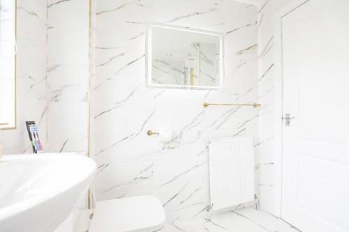 BishopbriggsDoralan的白色浴室设有白色大理石墙壁和白色浴缸。