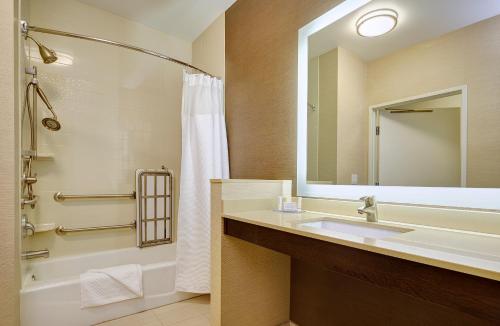 诺科科罗娜河畔/诺尔科费尔菲尔德套房酒店的一间带水槽、浴缸和镜子的浴室