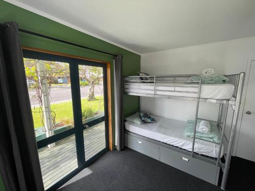 派西亚Peppertree Lodge & Backpackers的一间带双层床的卧室和通往阳台的门