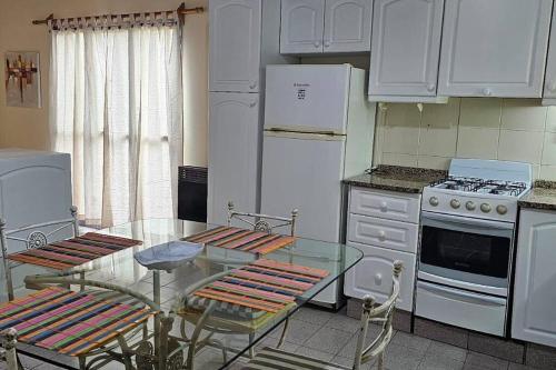瓜伊马延Departamento en Mendoza的厨房配有玻璃桌和白色家电