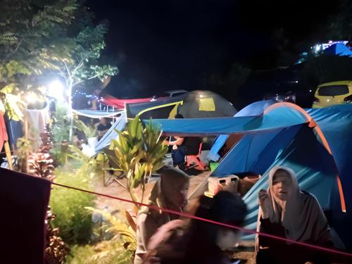 武吉丁宜Tapian Ratu Camp的一群人晚上坐在帐篷里