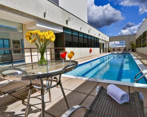 塔瓜汀加Flat 213 - Comfort Hotel Taguatinga的游泳池旁带玻璃桌椅的天井