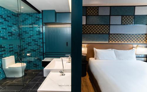米里Mercure Miri City Centre的一间卧室配有一张床,浴室设有水槽