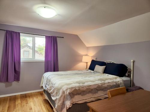 温尼伯Winnipeg Place to Stay的一间卧室配有一张床和一个带紫色窗帘的窗户