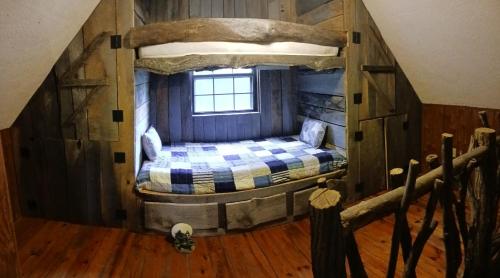 Rural RetreatThe Little Cabin on Huckleberry的木制客房的一张床位,设有窗户