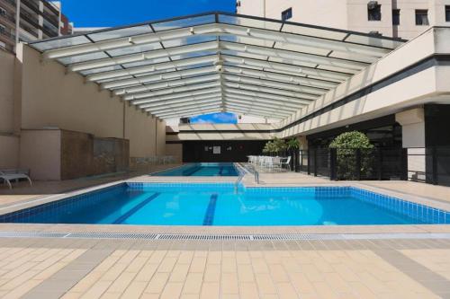 圣保罗Suite Congonhas - FLAT Aeroporto Congonhas的一座大型游泳池,旁边是一座建筑,设有遮阳篷