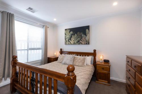 Christies BeachCozy Getaway, King Bed with TV, NBN, Netflix, Nespresso的一间卧室设有一张木床和一个窗户。