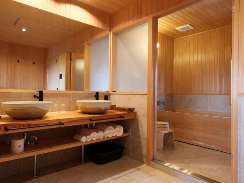 奈良NIPPONIA 田原本 マルト醤油的浴室配有2个盥洗盆和1个浴缸。