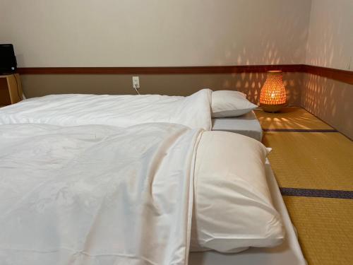 SukagawaKobohudonoyu的一间卧室配有两张带白色床单和灯的床