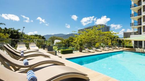凯恩斯凯恩斯太平洋大酒店的一座带躺椅的游泳池位于大楼旁