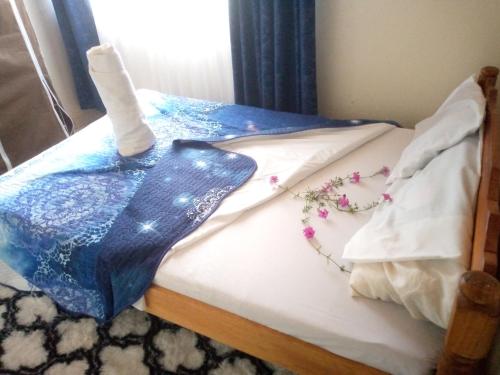 基苏木Pelia Rose Guesthouse的床上有蓝色的毯子和鲜花