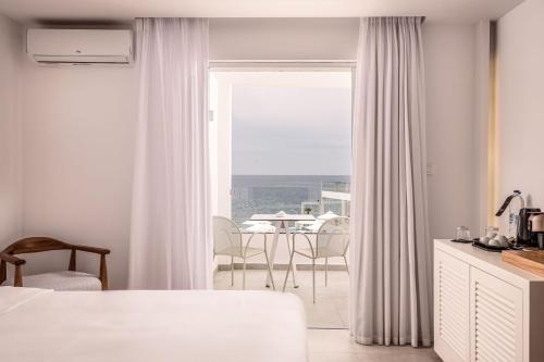 帕诺尔莫斯卡里莫斯Kantouni Beach Boutique Hotel的白色的客房设有窗户和桌椅