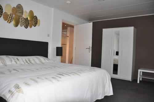 赫罗洛Het Voorhuis的一间卧室配有一张白色大床和黑色床头板