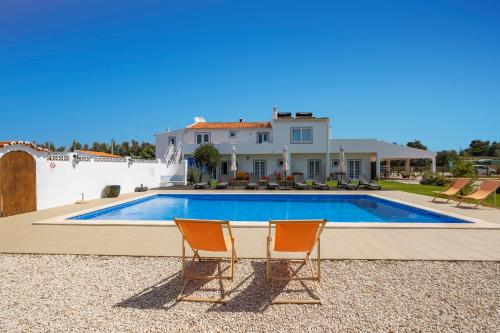 拉戈阿Casa Jardim Oasis的一座带游泳池和两把椅子的房子