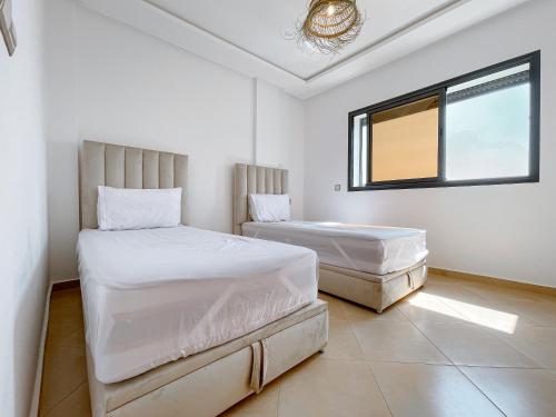 塔哈佐特La Perle Taghazout apparts 2-3px的白色客房的两张床,设有窗户