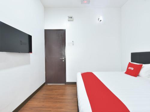 雪邦OYO 90869 Hotel Madeena Inn的一间卧室配有一张带红色毯子的床和一台电视。