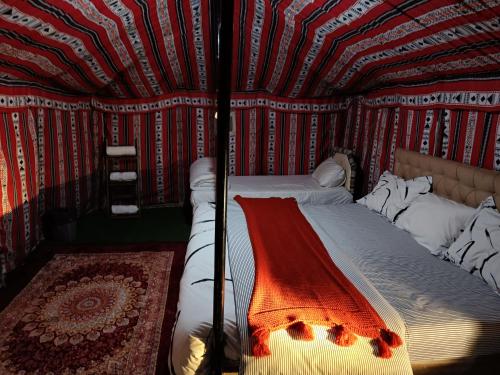 Al WāşilHamood desert local camp的一张位于带条纹墙的房间的床铺