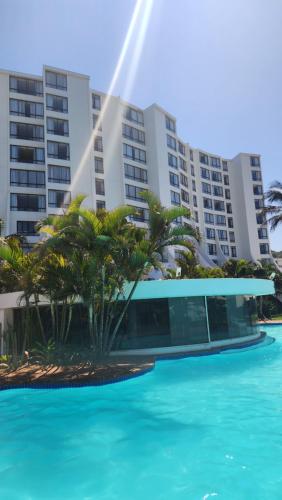德班Umhlanga Breakers Resort的一座楼前种有棕榈树的游泳池