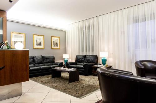 米兰柏林酒店的客厅配有黑色皮革家具和窗帘