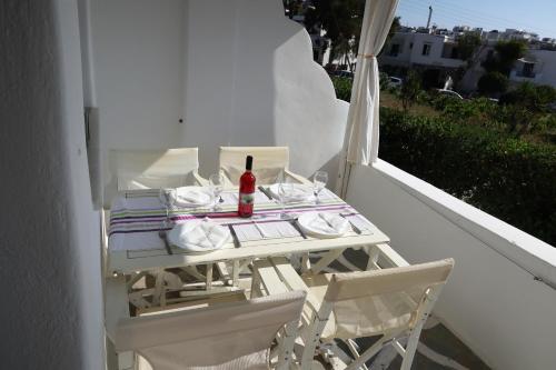 帕罗斯岛Afroditi studios的阳台上的白色桌子和一瓶葡萄酒