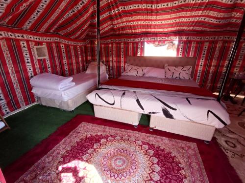 Al WāşilHamood desert local camp的圆顶帐篷内带两张床和地毯的房间