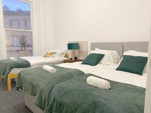 布里奇沃特Central Bridgewater Flat的一间卧室配有两张带绿色和白色床单的床