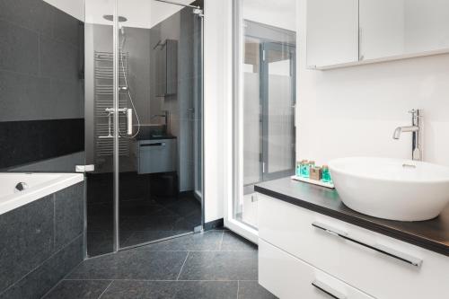 格拉茨Kaiser Apartments - Wohnpark Graz-Gösting的一间带水槽和玻璃淋浴的浴室