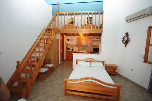 埃拉蒂尼Foinikas Rooms的一间卧室设有一张床和木制楼梯。