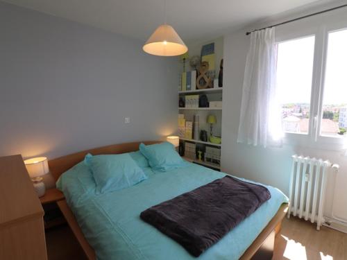 欧里亚克Appartement Aurillac, 2 pièces, 2 personnes - FR-1-742-389的一间卧室配有一张带蓝色床单的床和一扇窗户。