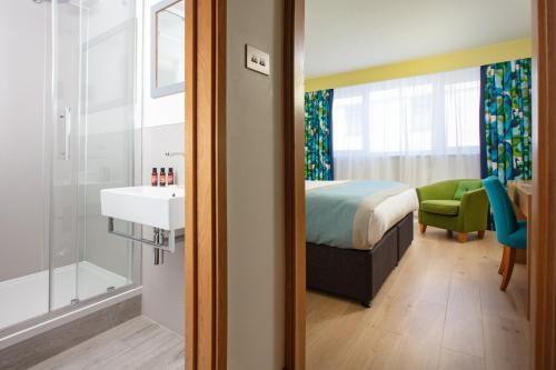 纽基布德卢森酒店及Spa的一间卧室配有一张床,浴室设有水槽