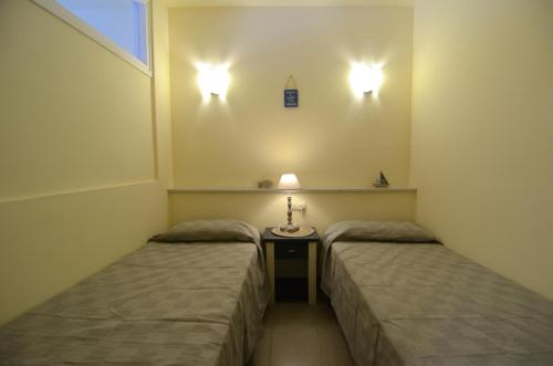埃斯塔蒂特JARDINS DEL MAR 12的配有桌子和灯的客房内的两张床